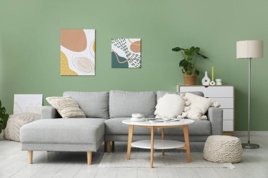 Rahat bir kanepe, kahve masası, oturma odasının içinde resimler ve lamba.