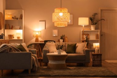 Oturma odasının içinde kanepeler, sehpa ve parlak lambalar var.