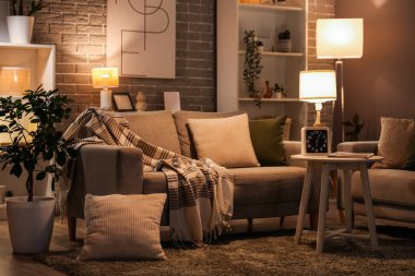 Sıcak kanepeler, sehpa ve oturma odasının içinde parlayan lambalar.