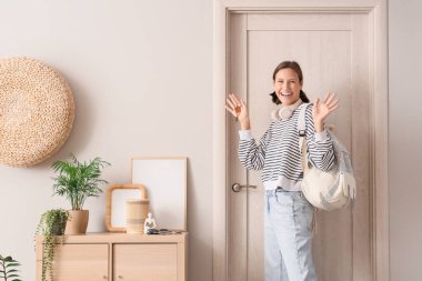 Koridorda el sallayan sırt çantalı ve anahtarlı genç bir kadın.