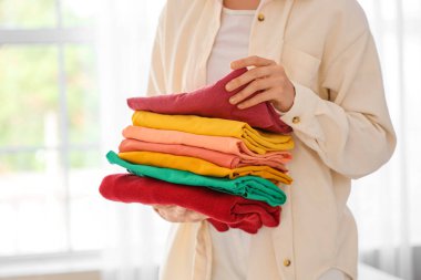 Genç bir kadın temiz giysileri evde tutuyor, yakın plan.