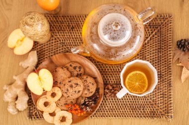 Çaydanlık, bir fincan yeşil çay, kurabiye tabağı ve sonbahar dekoru. Üst görünüm