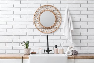 Banyo aksesuarları, ev bitkisi ve lavabo banyodaki beyaz tuğla duvarın yanında.