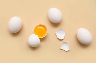 Bej arka planda tam ve kırılmış tavuk yumurtası.