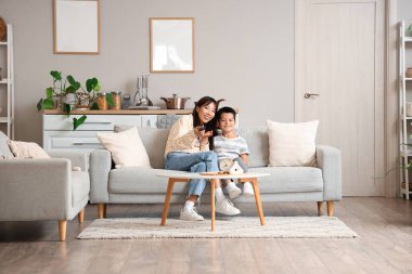 Genç anne ve küçük oğlu evde televizyon seyrediyor.