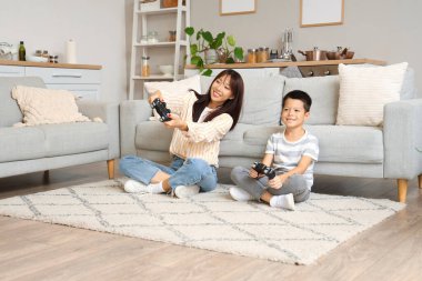 Genç anne ve küçük oğlu evde yerde video oyunu oynuyorlar.