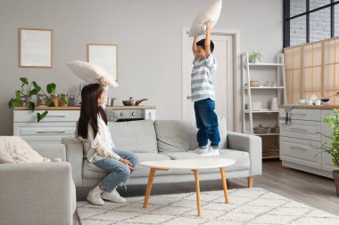 Genç anne ve küçük oğlu evde yastıklarla savaşıyor.