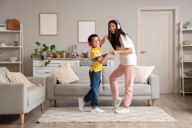 Mutlu genç anne ve küçük oğlu evde müzik dinleyip dans ediyorlar.