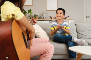 Genç anne evde oğluyla gitar çalıyor.