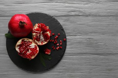 Taze olgun narı ve gri ahşap arka planda tohumları olan kara tahta.