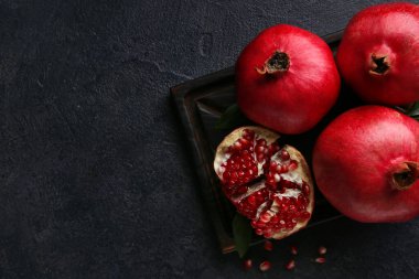 Koyu arkaplanda taze olgun nar bulunan tahta.