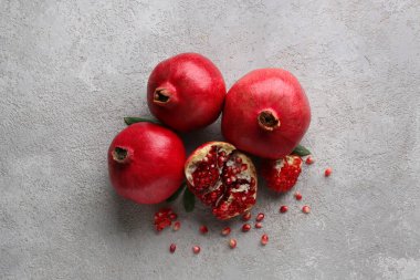 Gri zemin üzerinde tohumları olan taze olgun narlar.