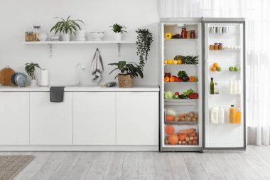 Modern mutfakta farklı taze ürünleri olan büyük açık buzdolabı.