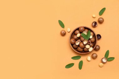 Lezzetli fındıklı ahşap kase ve turuncu arka planda yapraklar.