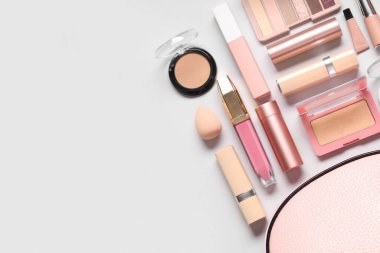 Gri arkaplanda farklı makyaj ürünleri bulunan kozmetik çanta