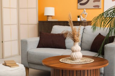 Modern oturma odasının içinde ahşap masalı gri kanepe.