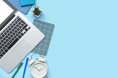 Renk arkaplanına bağlı modern dizüstü bilgisayar, kırtasiye ve alarm saati kompozisyonu