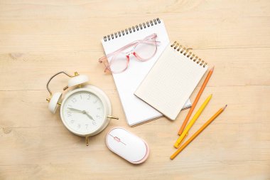 Ahşap zemin üzerinde kırtasiye, gözlük, çalar saat ve bilgisayar faresi bileşimi
