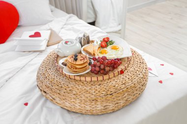 Sevgililer Günü için dekore edilmiş yatakta lezzetli kahvaltılı puf.