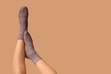 Kahverengi arka planda gri pamuklu çoraplı genç kadın bacakları