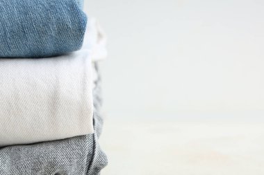 Beyaz arka planda farklı şık pantolon yığınları, yakın plan.