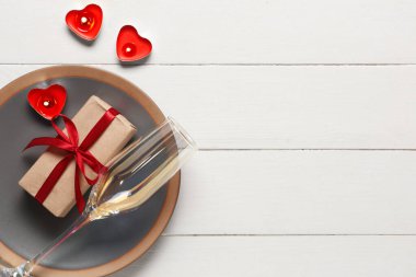 Hediye kutusu ve beyaz ahşap arka planda yanan mumlarla güzel bir masa. Sevgililer Günü kutlaması