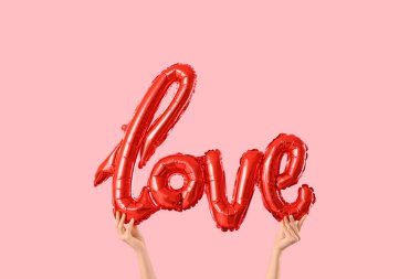 Balonlu kadın elleri pembe arka planda aşk kelimesi şeklinde. Sevgililer Günü kutlaması