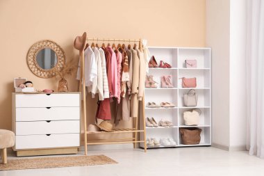 Farklı kadın kıyafetleri, ayakkabıları ve aksesuarları olan modern bir soyunma odası.