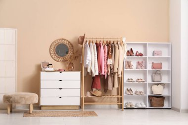 Farklı kadın kıyafetleri, ayakkabıları ve aksesuarları olan modern bir soyunma odası.