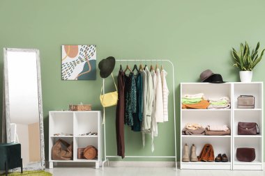 Modern giyinme odasının içinde şık kadın kıyafetleri, ayakkabıları, aksesuarları ve büyük aynaları var.