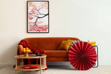 Çin Yeni Yılı için dekore edilmiş oturma odasının içinde kırmızı kanepe, masa ve boya var.