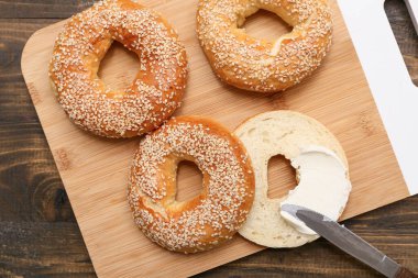 Tahta arka planda susam tohumlu lezzetli simit kesme tahtası