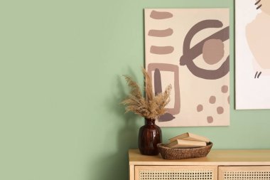 Çimenli çekmeceler, kitaplar ve odadaki yeşil duvardaki resim. Yakın çekim.