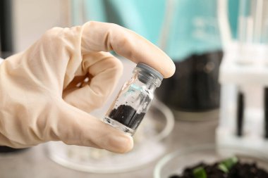 Laboratuvarda toprak numunesi taşıyan bir bilim adamı, yakın plan.