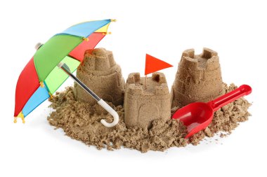 Beyaz arka planda kumdan kale, oyuncak kürek ve küçük şemsiye