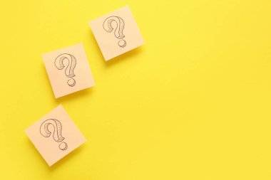 Renk arkaplanı üzerinde soru işaretleri olan yapışkan notlar