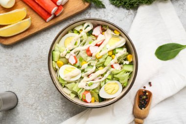 Yengeç saplı bir kase salata, buzdağı yaprakları, mısır, bıldırcın yumurtası ve grunge arka planda salatalık.