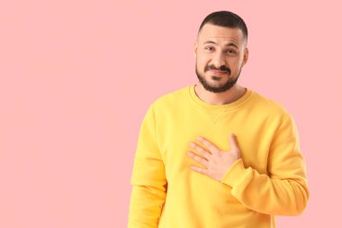 Pembe arka planda özür dileyen genç adam.