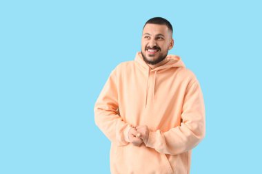 Mavi arka planda özür dileyen genç adam.