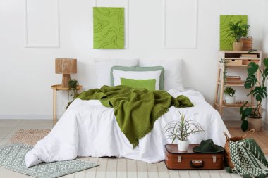 Bavulunda raf ve ev bitkisi olan modern şık bir yatak odası.