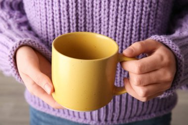 Sarı seramik bardak tutan kadın, yakın plan.