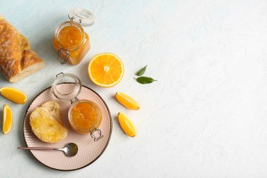 Kavanozlar dolusu tatlı portakal reçeli ve açık mavi arka planda dilimler.