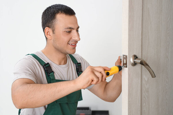 Работник мужского пола с отвёрткой для ремонта дверей дома