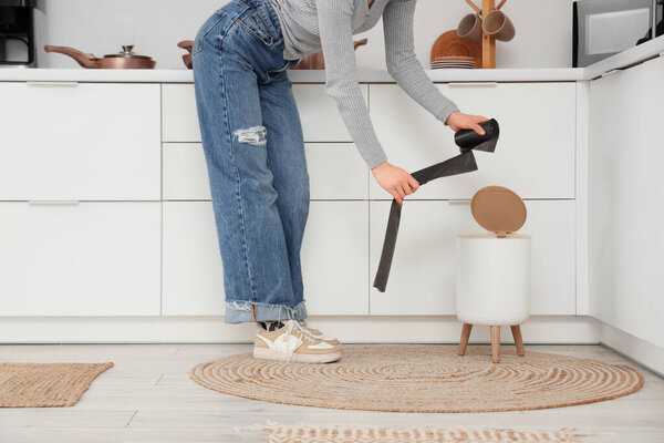 Женщина, заменяющая мусорный мешок в мусорном ведре дома