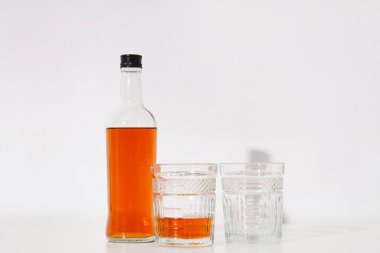 Beyaz arka planda şişe ve bir bardak rom.
