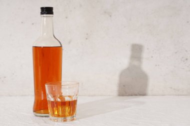 Beyaz zemin üzerinde buz küpleri olan bir şişe rom.