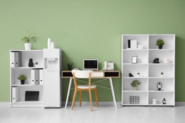 Modern su soğutucusu, çalışma alanı ve raf üniteleri olan şık bir ofis.