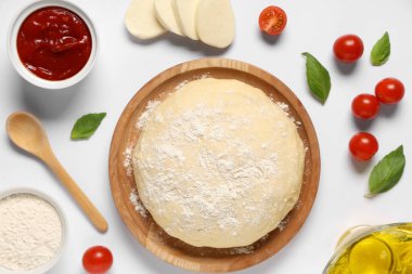 Mozzarella, ahşap tabak ve beyaz arka planda çiğ hamur ile pizza hazırlamak için gerekli malzemeler.