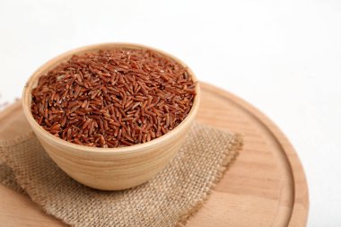 Tahta tahtada beyaz arka planda çiğ kahverengi pirinç kâseleri var.