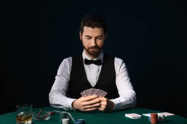 Poker fişleri ve kumarhanede kağıt oynayan yakışıklı bir bankacı.